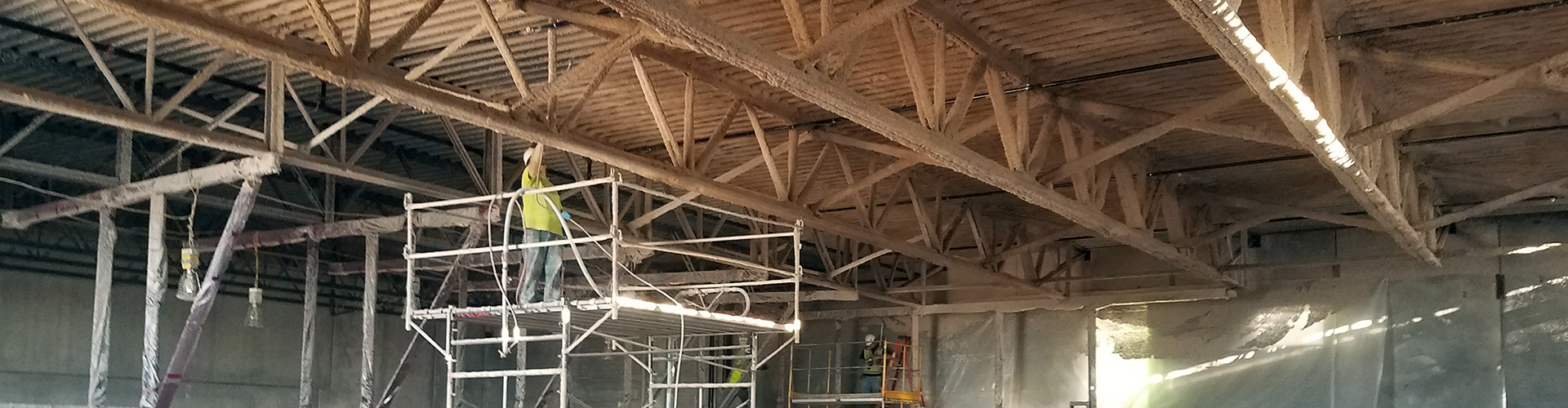 spray foam insulator on a lift installing fireproofing coating